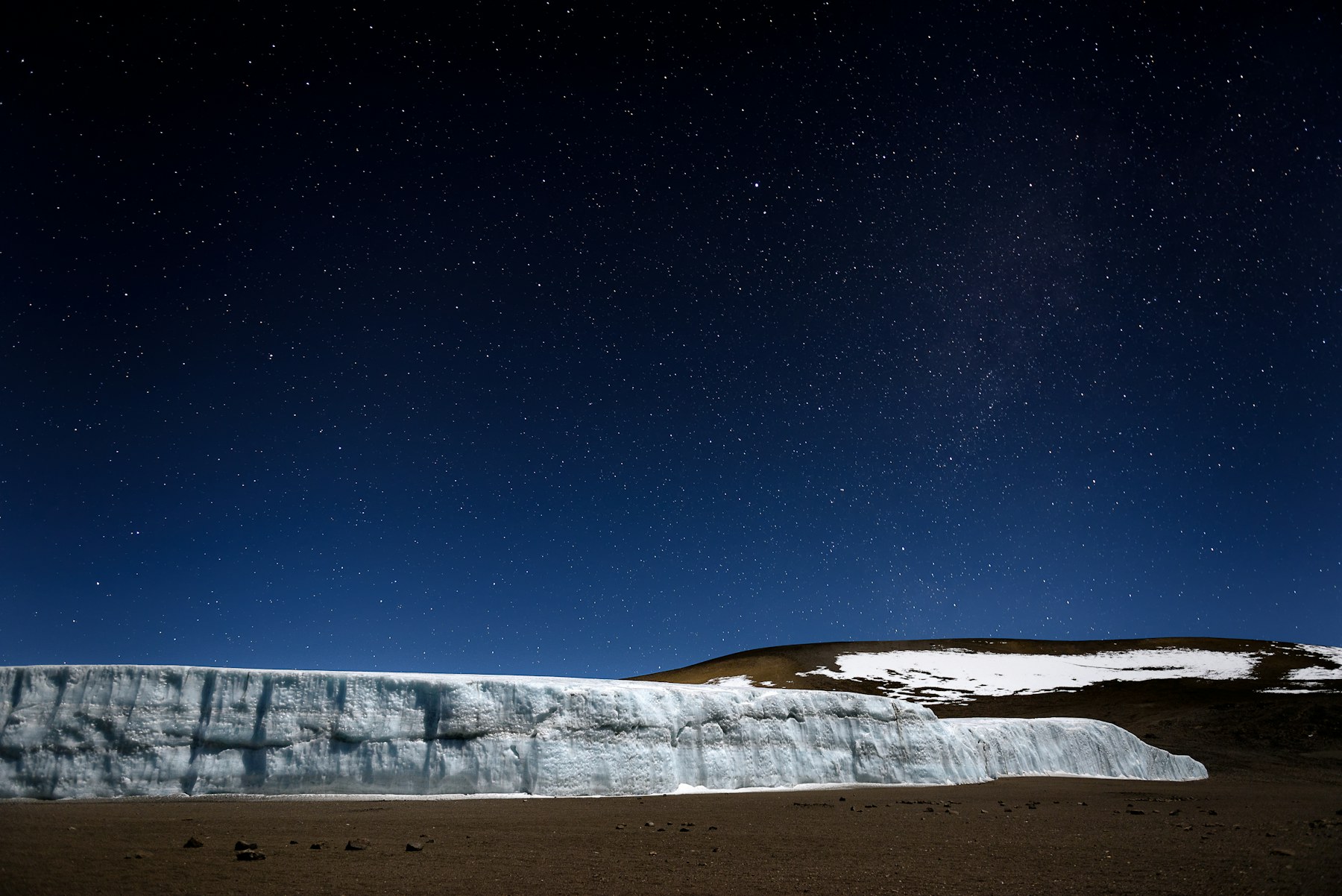 Glacier and star-filled night sky near the summit crater of Mount Kilimanjaro.