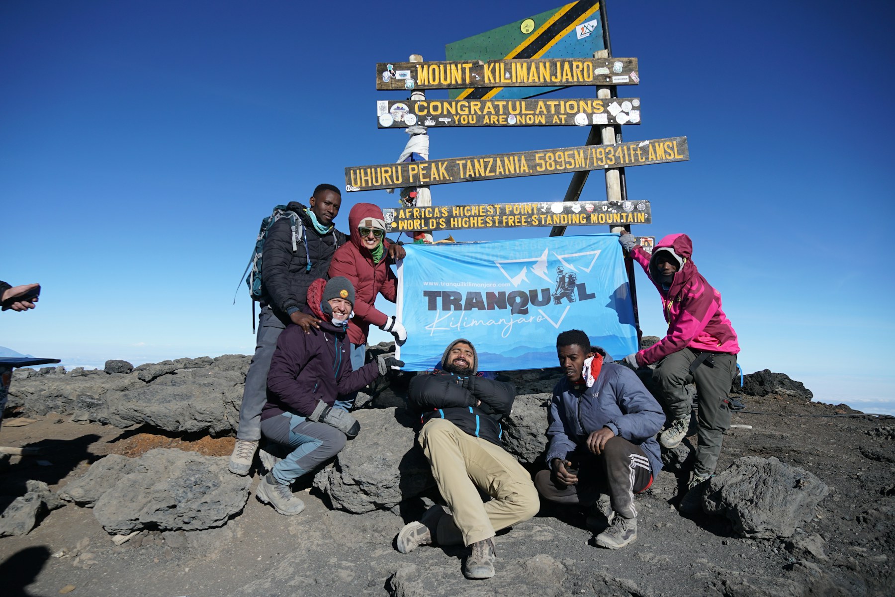 Climbers at the Uhuru Peak sign on Mount Kilimanjaro at 5,895 meters.
